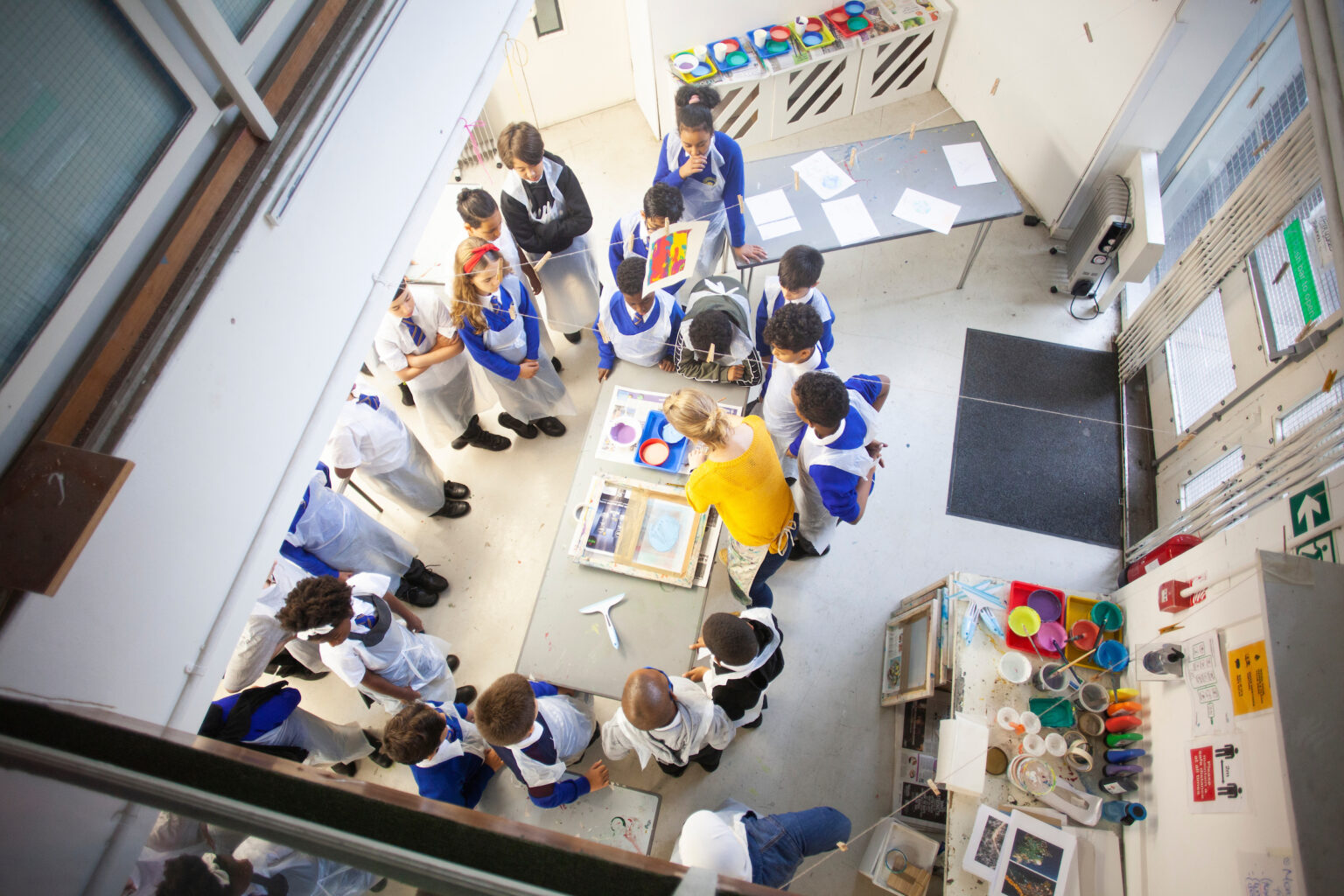 Overhead view of a primary school class watching a screen printing demonstration.