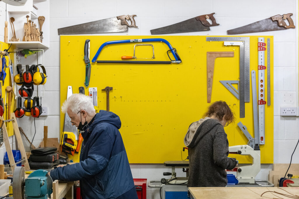 Two Maxilla Men's Shed members using different tools.