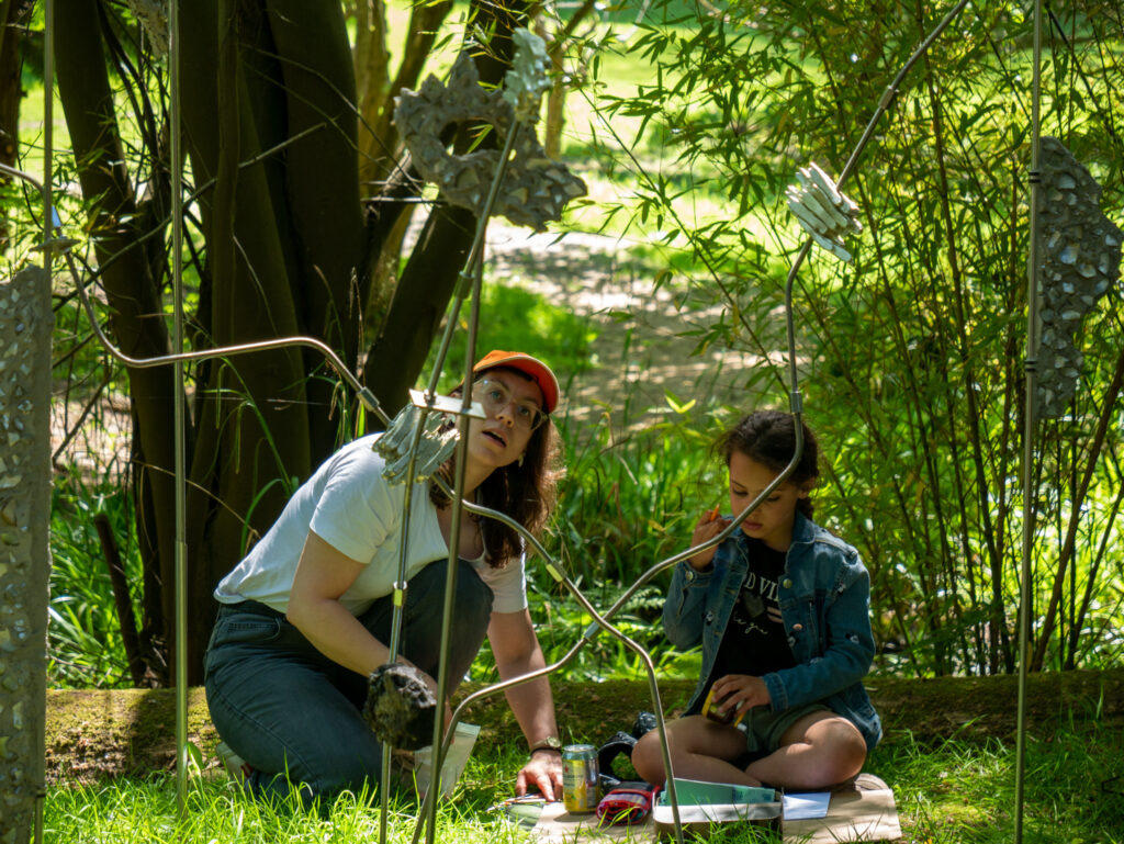 Artist and participant observing a sculpture from below.