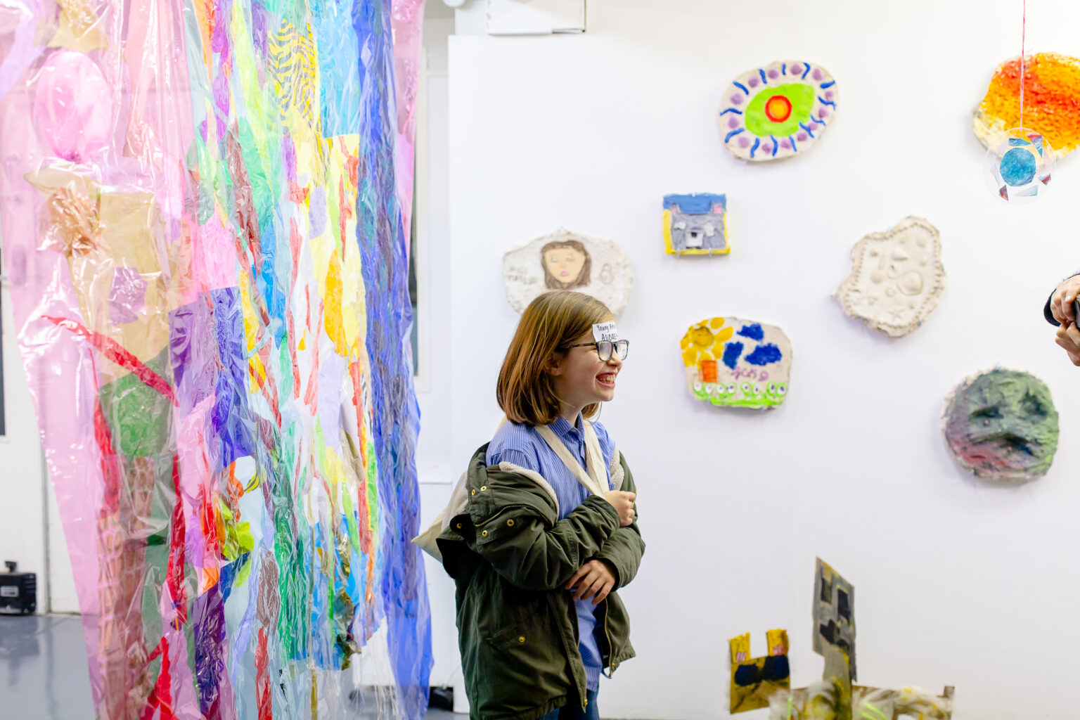 Programme participant smiling next to one of her exhibited artworks.