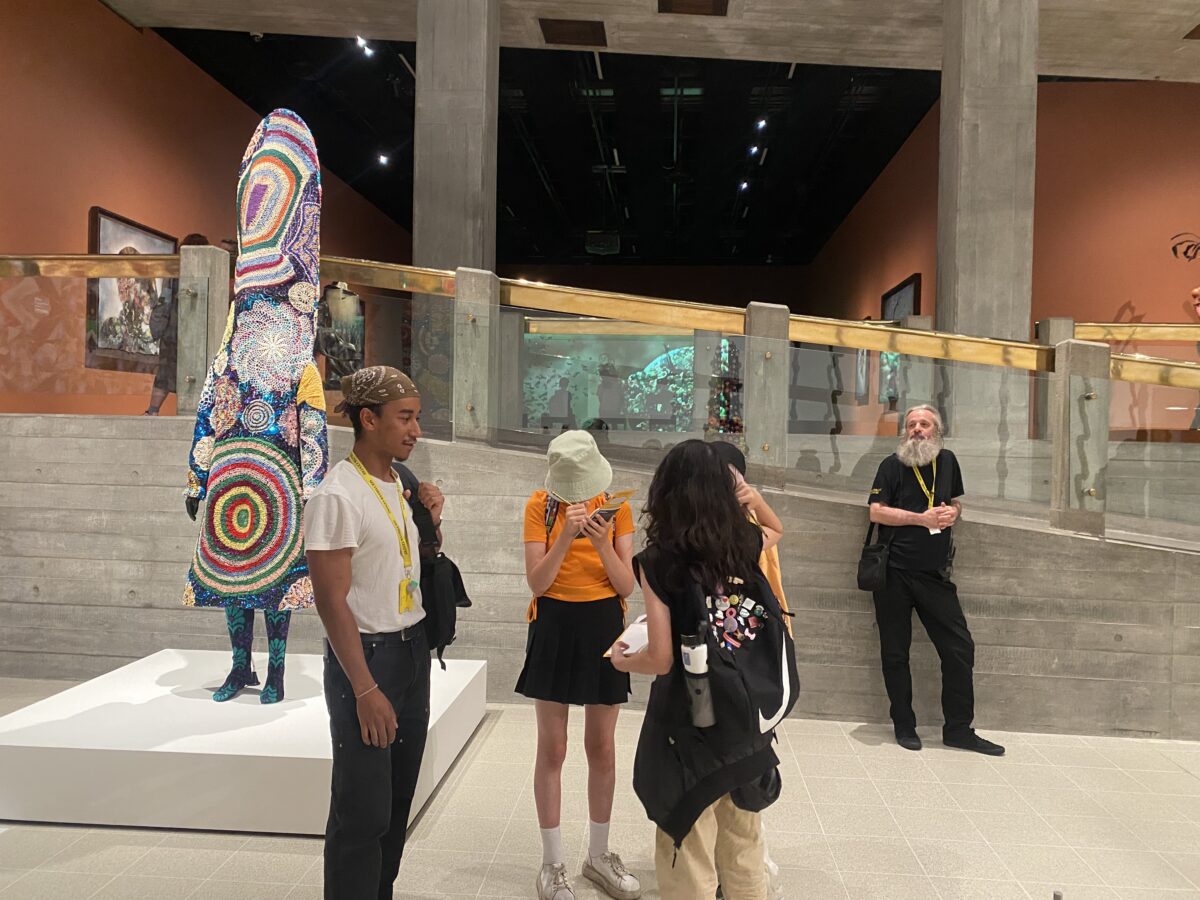 A group of children and Jack Rooney standing together inside In the Black Fantastic at the Hayward Gallery.