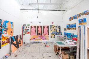 Large artist studio in use, colourful paintings hanging on the wall