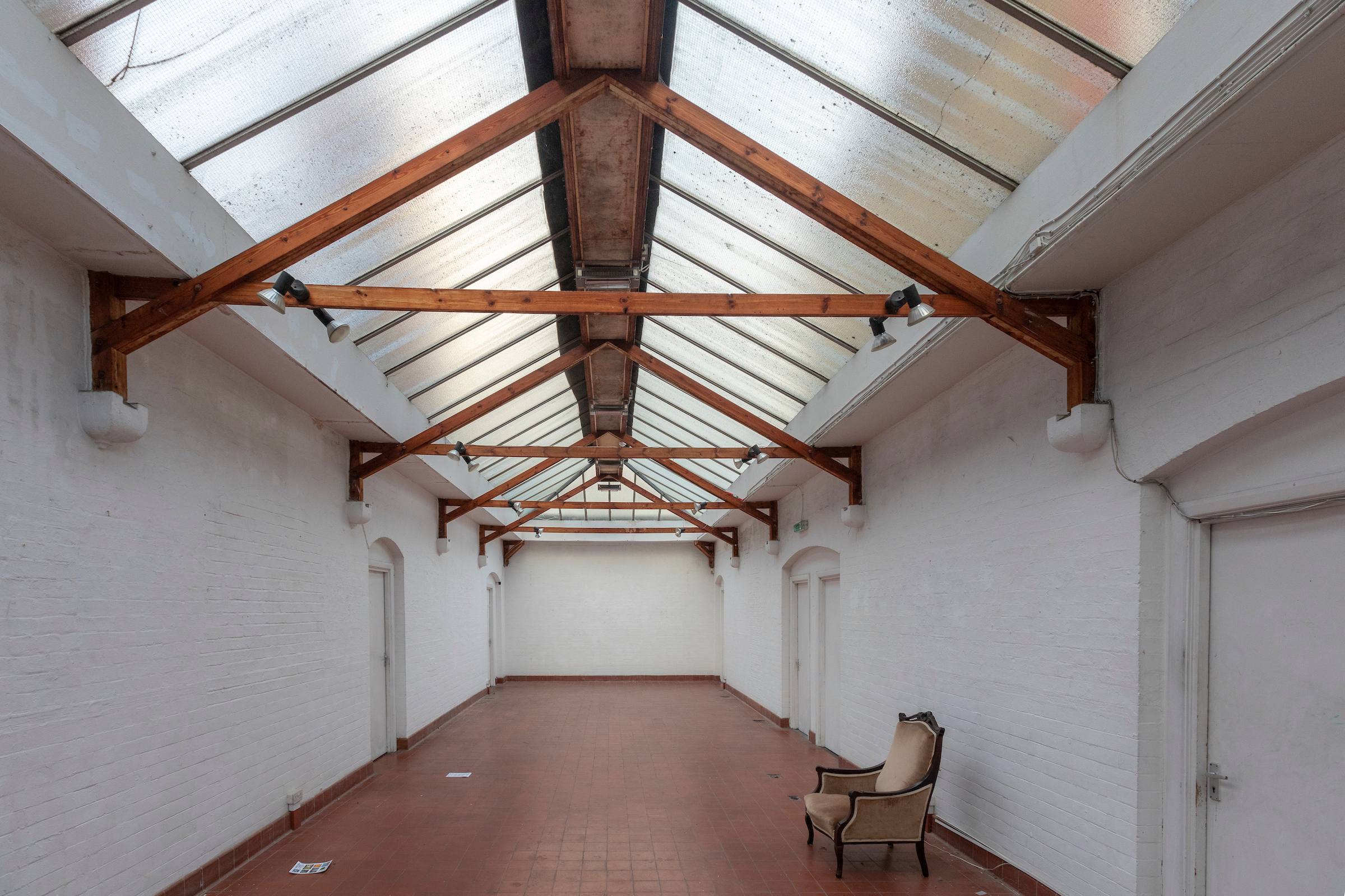Photograph of a bright gallery space, wooden beams and glass roof.