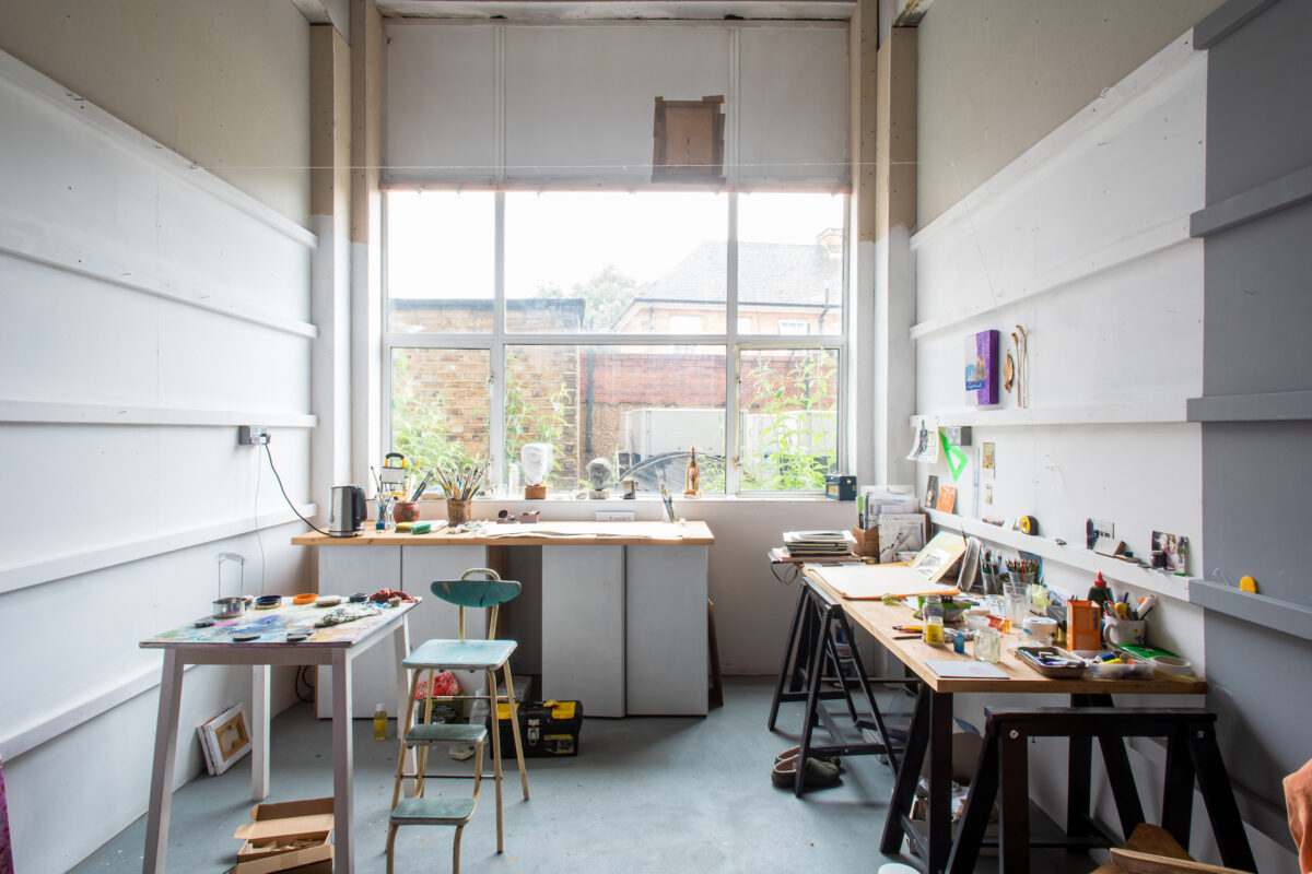 Photograph of a bright artists studio, a large window at the back