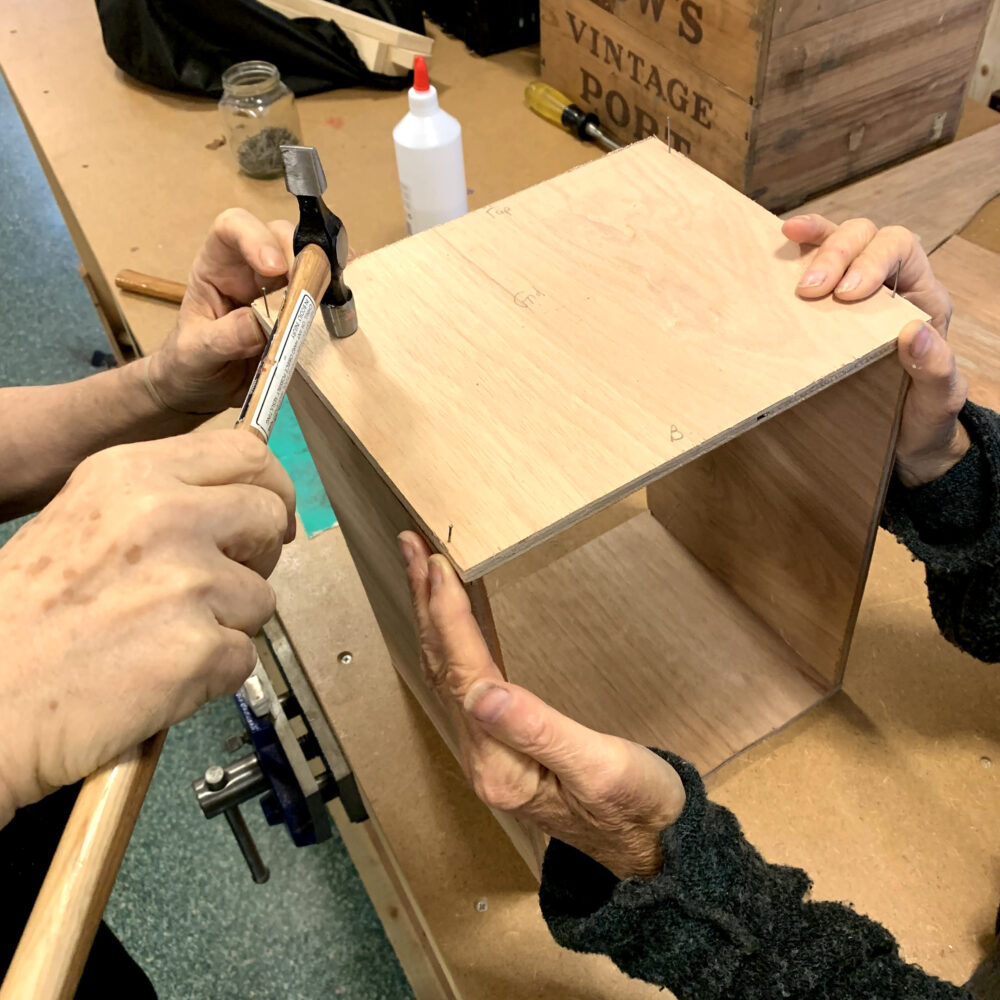 Close up of hands working together on a wooden DIY project, in a makerspace, indoors.