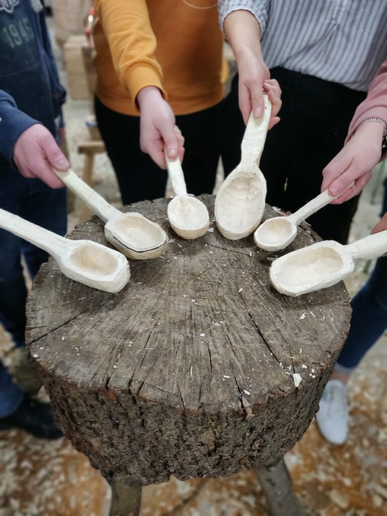 Close-up photograph of a group o people showing the camera their individually hand-carved spoons