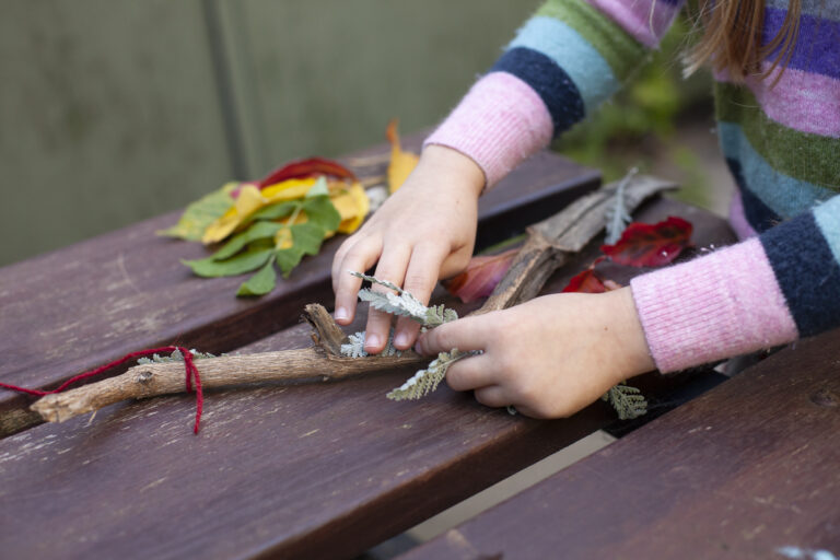 Flyer with info above and a photograph of a child's hands creating a magic wand out of sticks, leaves and thread.
