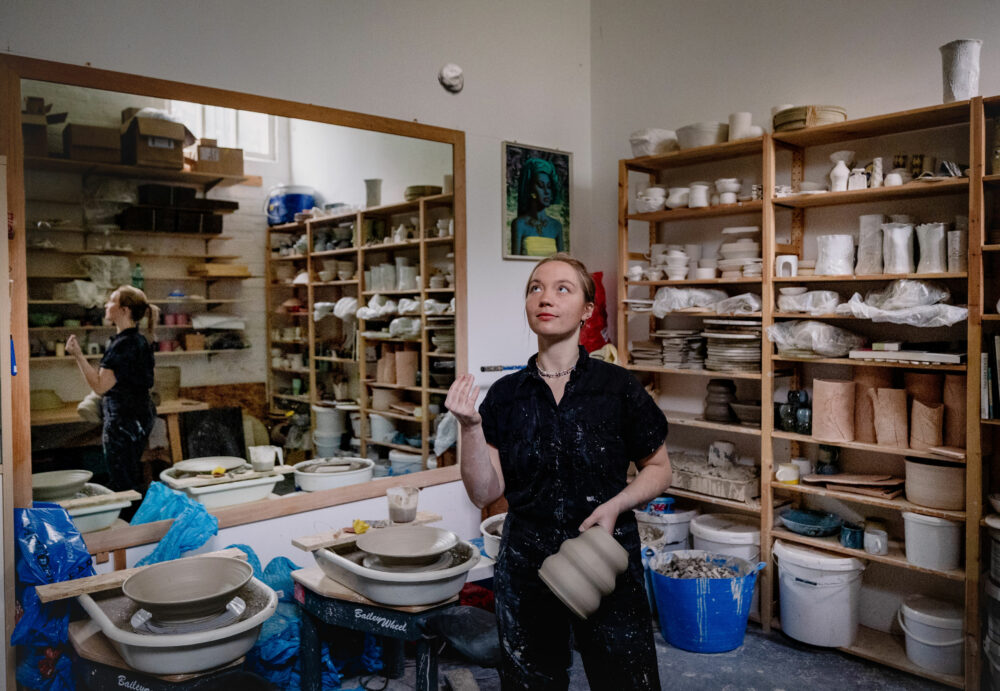 Portrait of Frankie in a ceramics studio throwing a small clay ball in the air