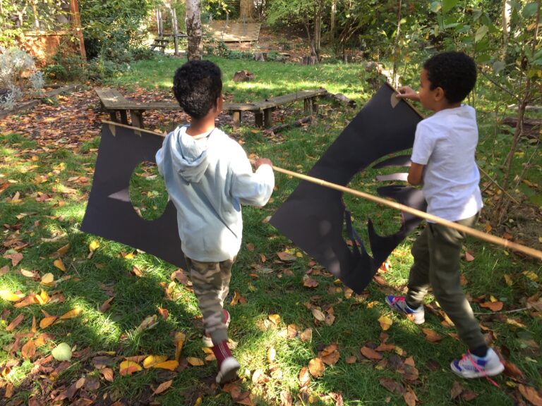 Photo of two children playing in the garden with two handmade black flags.