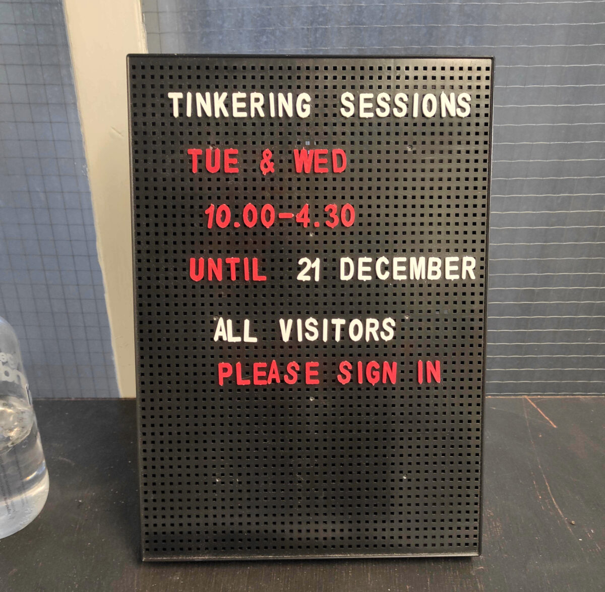 Close-up of a black peg letter board displaying the Shed's opening times in December.