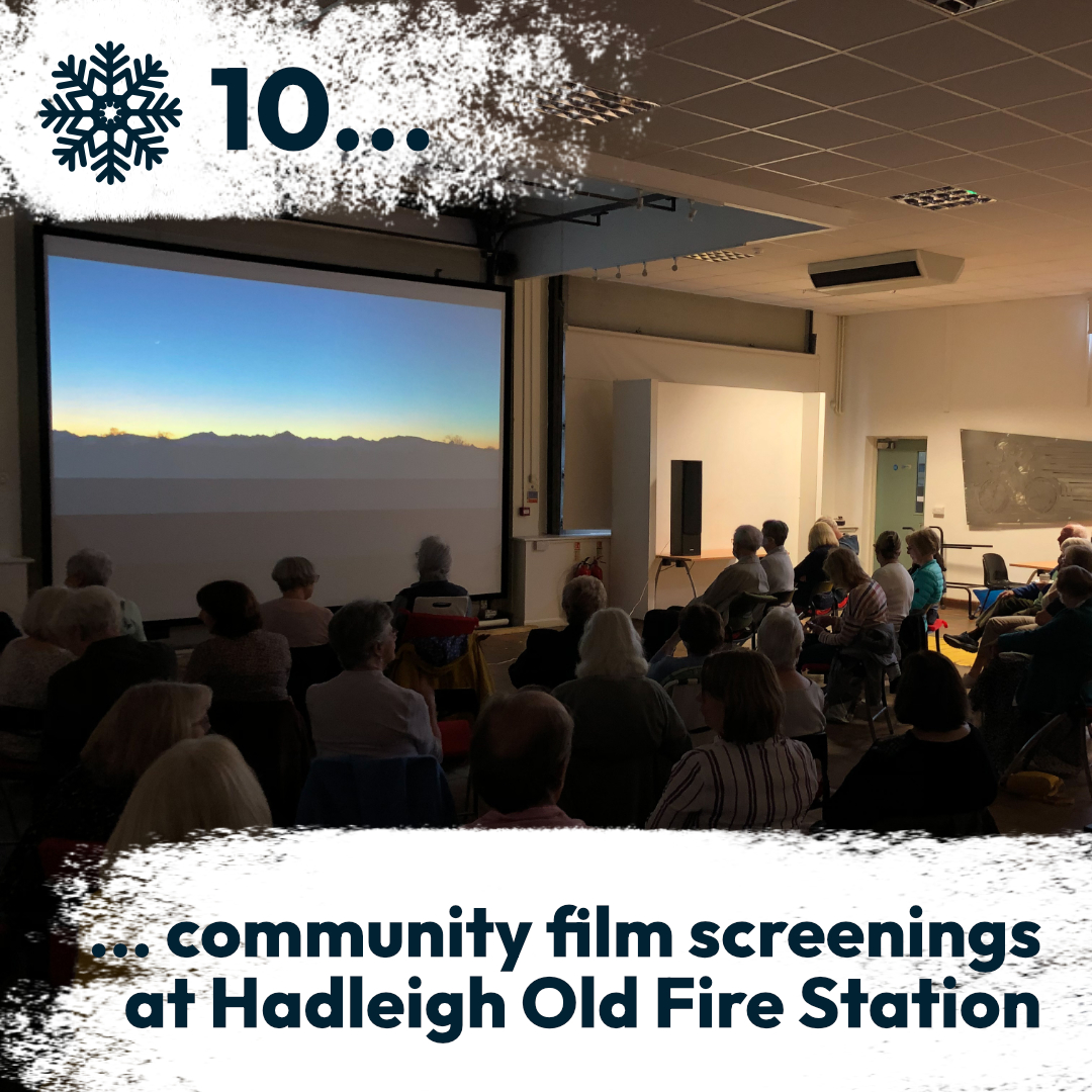 A film screening taking place in a large community hall with many people attending