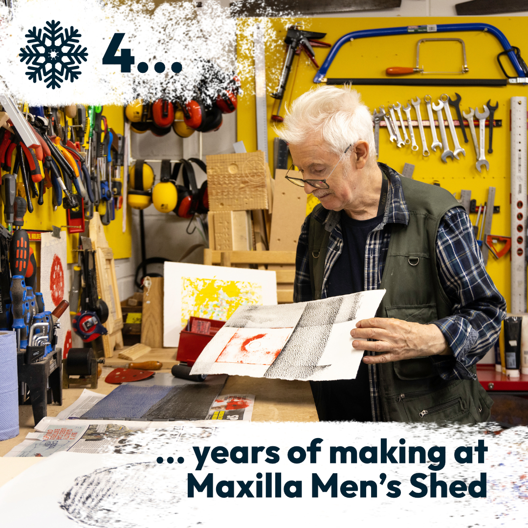 Shed participant looking at prints made during a printmaking workshop, in a community makerspace, indoors.