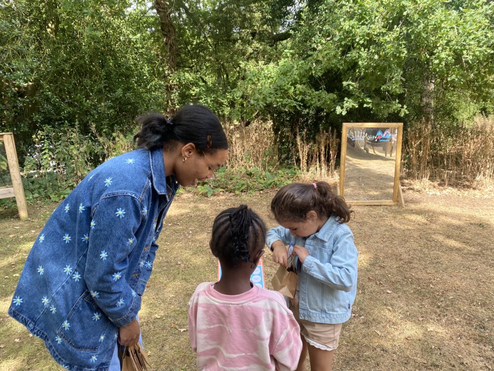Two young girls showing the Workshop Assistant the nature they have gathered in their bag.