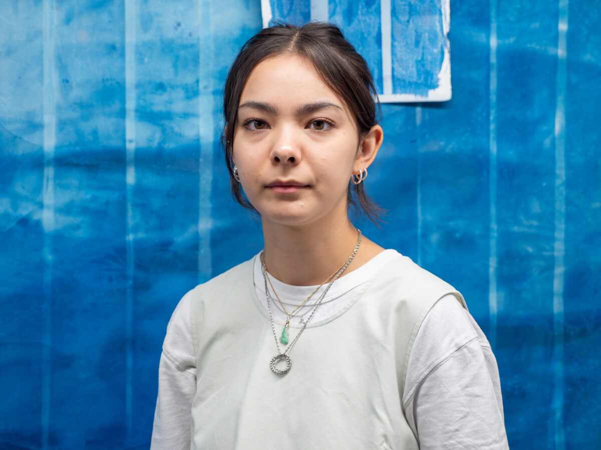 Close-up portrait of Francesca Telling against a cyan backdrop, part of one of her artworks.